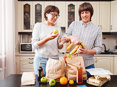 年轻夫妇正在厨房整理购买物品 产品一i女士男性女性食物互联网丈夫水果夫妻家庭成人图片