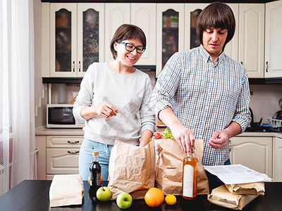 年轻夫妇正在厨房整理购买物品 产品一i男性送货女士成人妻子男人家庭橙子互联网夫妻图片