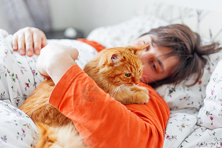 男人和姜猫在床上 可爱舒适的家庭背景 早安动物阳光时间宠物亚麻微笑情感就寝橙子哺乳动物图片