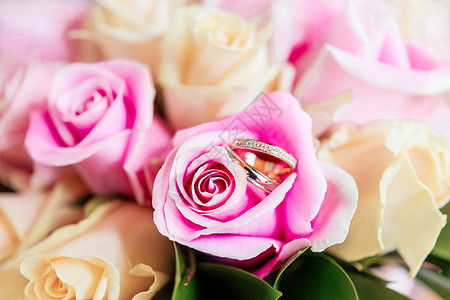 新娘花束上的金色结婚戒指与粉红色和黄色的玫瑰 用于婚礼的传统花卉组合 爱情和婚姻的浪漫象征假期作品配饰粉色植物图片