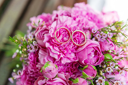 新娘花束上的金色结婚戒指 上面有粉色和淡紫色的玫瑰 用于婚礼的传统花卉组合配饰婚姻假期作品植物背景图片