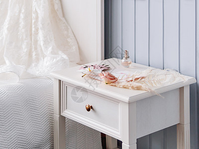 灰色的床边桌子 上面有新娘饰物 装饰性的怪兽叶和羊毛草 粉红玫瑰花 还有一瓶香水图片