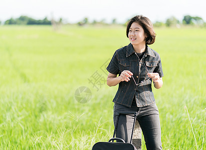 在公路上搭便车载行李的妇女旅游女士成人牛仔裤游客太阳镜青少年远足案件冒险背景