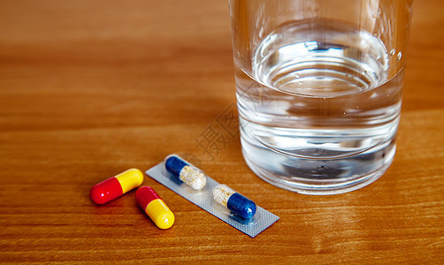 药用胶囊和桌上的一杯水保健科学家庭疼痛剂量抗生素药片桌子玻璃治疗图片