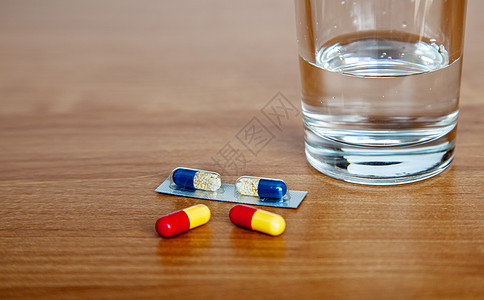 药用胶囊和桌上的一杯水药片卫生药物疼痛药品制药抗生素科学剂量桌子图片