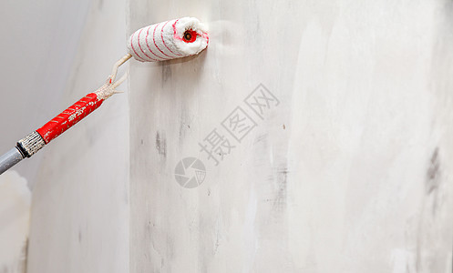 带胶水滚压闭板的工人油漆墙壁高清图片