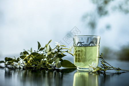 印度茉莉花或Juhi或在木质表面用透明玻璃和鲜花提取的甘油瓶子香气萃取酊剂植物叶子化妆品温泉治疗草本植物图片