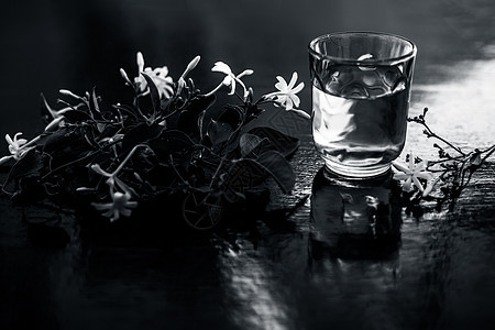 印度茉莉花或Juhi或在木质表面用透明玻璃和鲜花提取的甘油护理香味茉莉植物药品香气酊剂皮肤瓶子三叶草图片