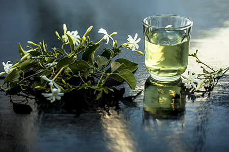 印度茉莉花或Juhi或在木质表面用透明玻璃和鲜花提取的甘油香气瓶子化妆品草本植物三叶草萃取叶子香味皮肤实验室图片