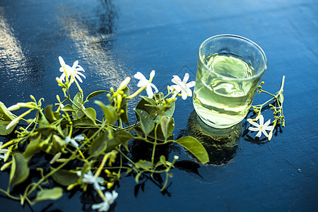 印度茉莉花或Juhi或在木质表面用透明玻璃和鲜花提取的甘油萃取三叶草温泉皮肤草本植物香气植物茉莉护理化妆品图片