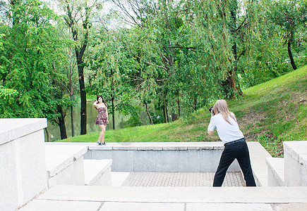 摄影师带一个女人站在公园的楼梯上图片