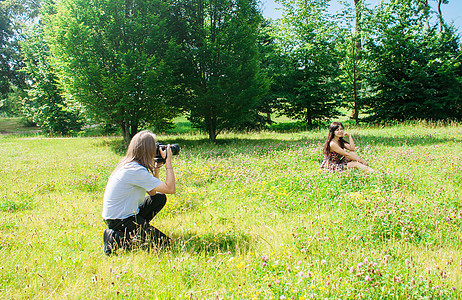 摄影师带一个女人坐在公园的草地上图片