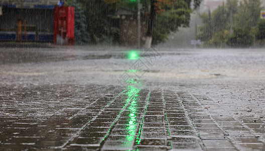 在人行道和柏油路的大雨被绿色红绿灯照亮气候液体反射城市路面沥青季节路口地面水坑图片