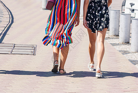 两名女孩在街上走着裙子朋友晴天人行道太阳城市牛仔裤女性快乐友谊图片