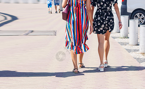 两名女孩在街上走着女性晴天人行道短裤成人太阳友谊牛仔裤假期朋友图片