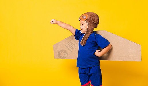 小男孩笑笑 戴着飞行员帽子玩耍 带着玩具卡的护目镜喷射男生超级英雄飞机幸福领导者孩子纸板创新动机图片