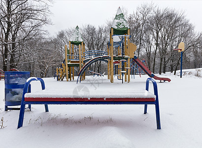 在操场上摇摆时被雪覆盖公园青年凉亭蓝色降雪秋千花园院子季节房子图片