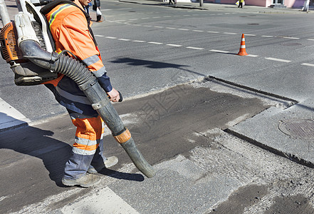 工人用一个工业真空清洁工清理道路的坏路段 对沥青路部分进行部分维修家庭压缩机械压力鼓风机男性吹叶机塑料沥青噪音图片