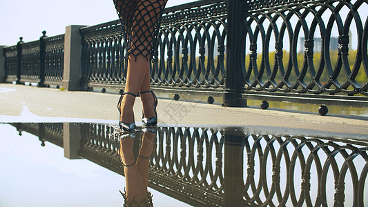 穿着高跟鞋的女子腿在水坑中行走图片