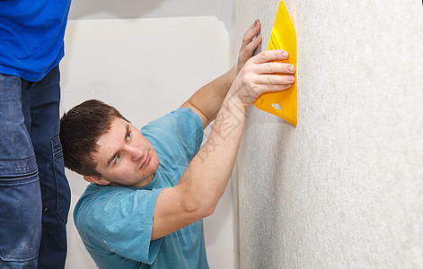 青年工人平滑的壁纸男性装修绘画胶水安装墙纸维修家务风格条纹图片