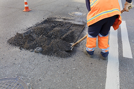 工人在道路建设中用铲子清理部分沥青路面图片