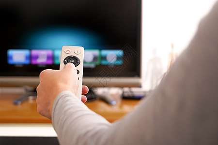 一个女人手拿着客厅电视盒的遥控器手指控制电子互联网屏幕渠道技术视频控制板电影图片