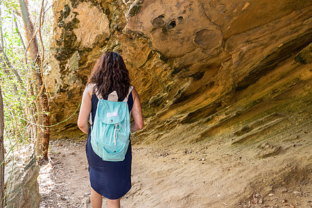 女人在一块大岩石下行走建筑学目的地砂岩旅行遗产场景冒险隧道荒野公园图片