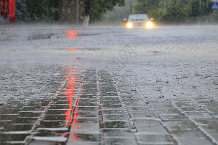 红灯照亮了人行道和沥青路上的大雨住宅街道下雨红绿灯建筑物反射流动波纹路面水坑图片