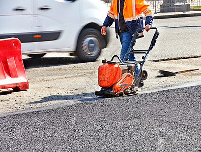 道路修理期间 一名路务工人用汽油振动压实机压缩沥青图片