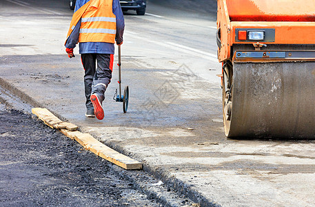 在路上工作的道路工程师用电子测量轮测量道路图片