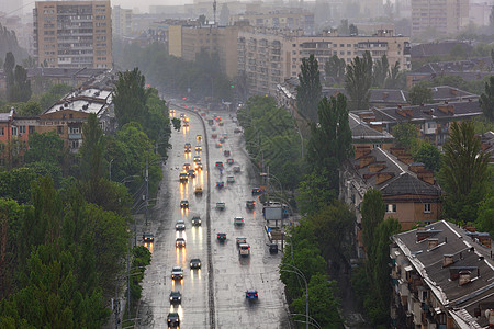 在旧城居民区和街道的暴雨中 一辆经过汽车而过往的潮湿公路上反射车灯头灯图片