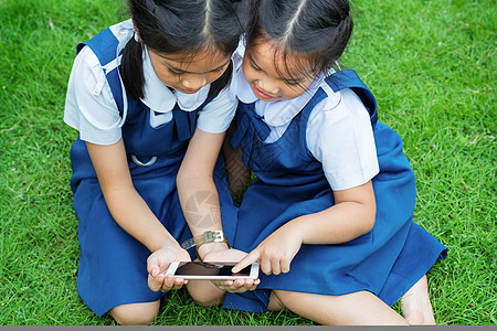 两个小妹妹女孩在互联网上玩手机智能手机游戏乐趣童年团体朋友们公园花朵孩子家庭教育场地图片
