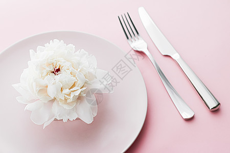 餐盘和餐具 配有小鲜花作为婚礼装饰品 放在粉红色背景 活动装饰最上桌菜以及甜点菜单新娘品牌奢华厨师派对礼物晚餐推广广告用餐图片