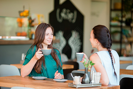 快乐笑容的年轻女子在咖啡馆喝咖啡 交流和友谊概念耳语女士城市朋友顾客咖啡店桌子青少年女性女朋友图片