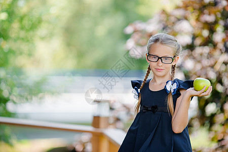 可爱的小女孩 在户外吃绿苹果 回到学校的概念中去领带女性午餐起动机工作簿女学生女孩桌子铅笔乐趣图片