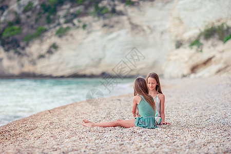 女孩暑假期间在热带海滩玩得开心的小女孩享受姐姐海景闲暇幸福卵石友谊婴儿海滨孩子们图片