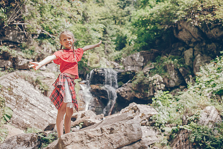 小女孩享受着瀑布的风景娱乐热带吸引力婴儿丛林女孩乐趣童年假期公园图片