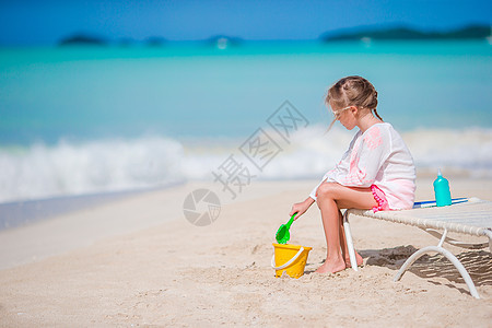 可爱的小女孩在海滩度假时玩玩具 小孩玩沙子图片