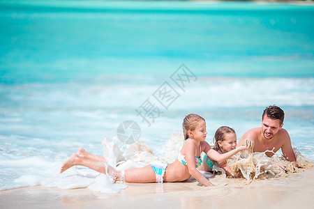父亲和小孩享受海滩夏季热带度假 在浅水中玩耍的沙滩夏假图片