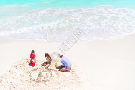 家庭在热带白色海滩建造沙滩城堡父亲玩具父母喜悦男人乐趣支撑女孩孩子海岸线图片