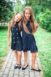 两个可爱的小女孩 在学校门口摆着姿势 装模作样娱乐朋友友谊同学乐趣学习幸福大学学生双胞胎图片