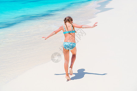 海滩度假时穿泳衣的可爱小女孩童年海岸线闲暇蓝色支撑幸福泳装热带太阳情调图片