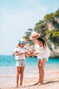 母亲在热带海滩对女儿施防晒霜 以保护她的女儿假期护理晒斑享受身体婴儿支撑童年紫外线海岸图片