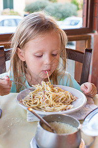 可爱的小女孩在户外休息时吃意大利面晴天餐厅乐趣烹饪勺子盘子女性家庭厨房院子图片