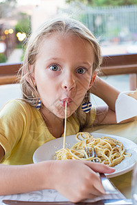 可爱的小女孩在户外休息时吃意大利面盘子面条胡椒童年午餐幸福卷曲食欲晴天婴儿图片