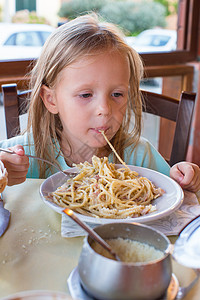 可爱的小女孩在户外休息时吃意大利面幸福食欲面条婴儿孩子们女性烹饪桌子勺子食物图片