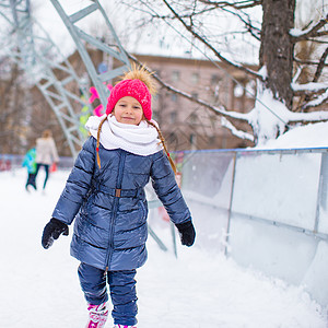 可爱的小女孩滑冰 在户外溜冰场微笑运动童年速度女性生活方式女孩套装企鹅溜冰者图片