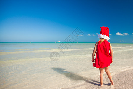 热带海滩上戴着红色圣诞老人帽子的小可爱女孩卡片女儿童年幸福戏服假期异国孩子情调朋友图片