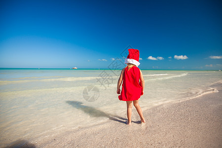 热带海滩上戴着红色圣诞老人帽子的小可爱女孩季节闲暇女儿朋友游泳戏服海报姐姐孩子异国图片
