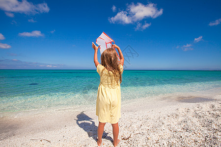 快乐的小女孩在热带沙滩度假期间玩飞风筝游戏支撑孩子假期女孩天空跑步女性海滨闲暇童年图片